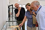 Foto von drei Personen in der Ausstellung der Gedenkstätte vor einer Vitrine mit Effekten von ehemaligen Häftlingen