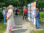 Mehrere Workshop-Teilnehmende stehen vor der Plakatwand des Ort der Verbundenheit während eine Person vom Projektteam zu ihnen spricht.