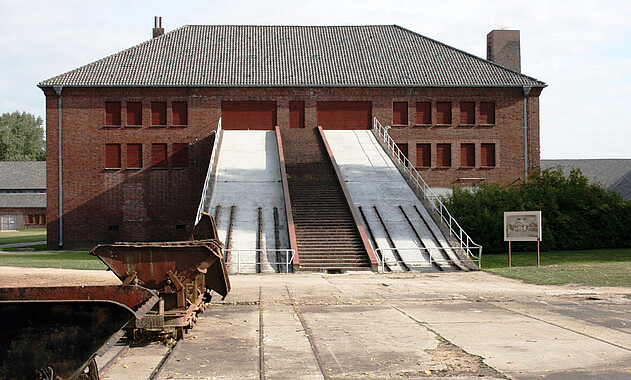 Foto von Loren vor der Rampe des ehemaligen Klinkerwerks. Foto: KZ-Gedenkstätte Neuengamme, 2009.