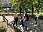 vier Personen stehen in einem Park und schauen auf eine Tafel