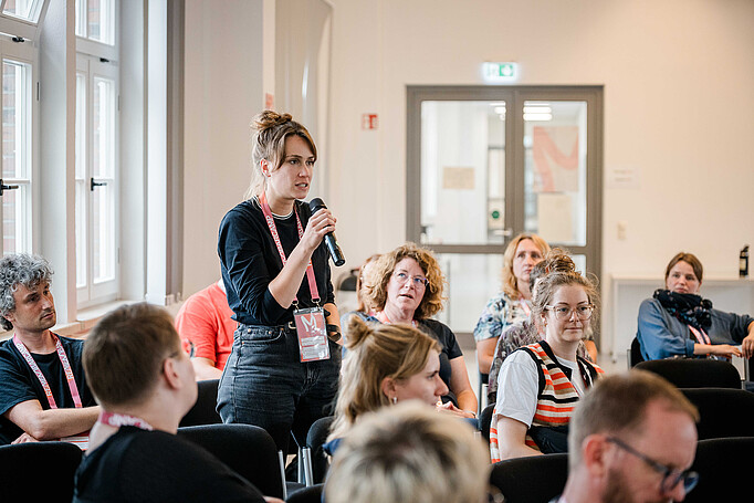 Auf dem RememBarcamp 2026 spricht eine Person in ein Mikrofon, andere Personen hören zu
