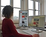 Rücken einer Person, die an einem Schreibtisch sitzt, auf dem PC ist die webseite der KZ-Gedenkstätte Neuengamme angezeigt