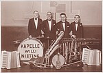 Schwarz-weiß Foto: Vier Männer in Anzügen mit Fliege, vor ihnen Instrumente, auf der Basstrommel steht Kapelle Willi Nieting