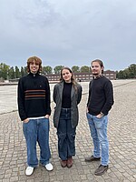 Es stehen die drei Freiwilligen Philipp, Uliana und Gabriel auf dem ehemaligen Appellplatz der KZ-Gedenkstätte Neuengamme