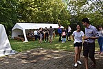Junge Menschen stehen verteilt auf einer Wiese, im Hintergund ein Zelt.
