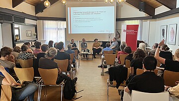 Rücken der Teilnehmenden und eine Präsi