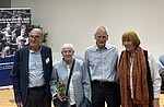 Vor der Veranstaltungsbühne stehen lächelnd Arm in Arm und von links nach rechts Jean-Michel Gaussot, Yvonne Cossu-Alba, Ulrich Gantz und Barbara Brix .