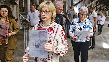 Präsentation der Druckplatten für den „Ort der Verbundenheit“, 2. Mai 2026, zu sehen mehrere Personen, die Druckplatten in den Händen halten, im Vordergrund eine Frau mit Brille und weiß-rotem Oberteil