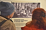 Zwei Besuchende stehen in der Ausstellung am Geschichtsort Stadthaus vor einer schwarzweiß Fotografie mit dem Text Fotografien einer Hamburger Deportation im Oktober 1941