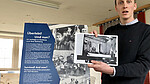 Foto von Lennart Onken im Depot der KZ-Gedenkstätte Neuengamme vor einer Ausstellungstafel
