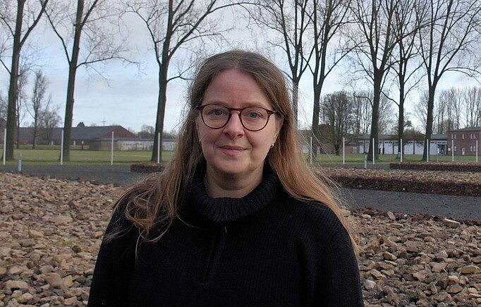 Susann Lewerenz hat lange Haare und trägt eine Brille. Im Hintergrund Bäume.