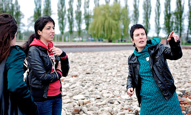 Bild von einer Gedenkstättenpädagogin, die das Gelände erläutert. Foto: Mark Mühlhaus, attenzione photographers, 2010.
